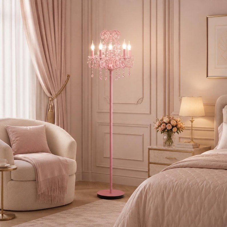 May include: A pink floor lamp with a chandelier design. The lamp has five candle-style lights and crystal accents. The lamp is in a bedroom with a cream-coloured chair, curtains, and a bed. The lamp is approximately 152 cm tall.