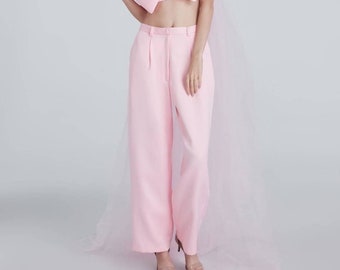 Peut inclure: Une tenue rose avec un haut à nœud volumineux et un pantalon large. La tenue est associée à une superposition rose transparente.