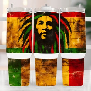 May include: Three stainless steel tumblers with a white handle and lid. Each tumbler features a distressed wood background with a red, yellow, and green color scheme. The center tumbler has a black and white image of Bob Marley's face with dreadlocks.