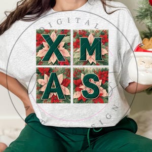 May include: A white t-shirt with a green and red Christmas design. The design features the letters XMAS in a block style with poinsettia flowers and green leaves.