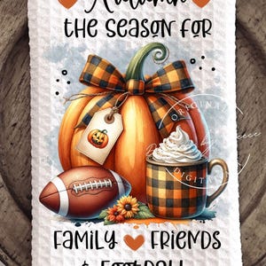 May include: White kitchen towel with an autumn-themed design. Features a large orange pumpkin with a plaid bow, a football, and a mug of whipped cream. Text reads "Autumn the season for family, friends & football."