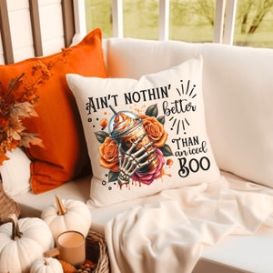 May include: White throw pillow with a skeleton hand holding a pumpkin spice latte with the text "Ain't nothin' better than an iced boo".