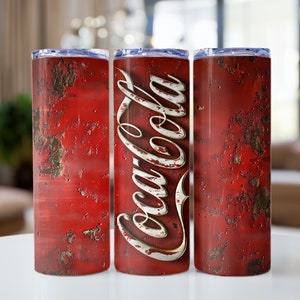 May include: Three stainless steel tumblers with a red, rusty, distressed design and the Coca-Cola logo in white.