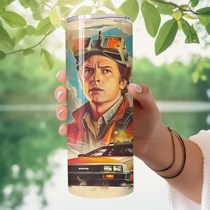May include: A stainless steel tumbler with a colorful illustration of a man wearing goggles and a futuristic car. The man has brown hair and is wearing a red jacket. The car is a silver DeLorean with a red interior.