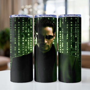 May include: A black and green tumbler with a graphic of a man wearing sunglasses and a black coat. The background is a green matrix code.