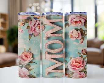May include: Three stainless steel tumblers with a floral design and the word "MOM" on the middle tumbler. The tumblers have a light blue background with pink roses and green leaves.