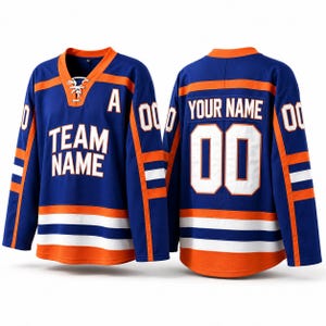 Può includere: Una maglia da hockey blu con dettagli arancioni e bianchi. La maglia presenta la scritta "TEAM NAME" sul davanti e "YOUR NAME" e il numero "00" sul retro. Ha un colletto allacciato.