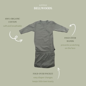 May include: A light gray organic cotton baby swaddle with fold-over hands and a fold-over pocket. The swaddle is designed to prevent scratching and make diaper changes easier. The text "100% Organic Cotton" and "soft and breathable" is visible on the image. The text "LITTLE BELLWOODS" is also visible on the image.
