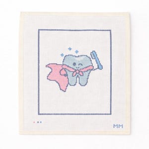 May include: Cross-stitch artwork featuring a smiling tooth character with a pink cape and bow tie, holding a blue toothbrush. The tooth is light blue with a happy face, surrounded by blue sparkles. The design is framed by a dark blue border on a white background.