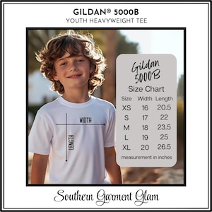 May include: A white Gildan 5000B youth heavyweight tee size chart with width and length measurements in inches. The chart lists sizes XS through XL with corresponding dimensions ranging from 16 to 20 inches in width and 20.5 to 26.5 inches in length.