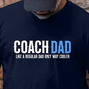 May include: A navy blue t-shirt with white text that reads "Coach Dad Like a regular dad only way cooler".