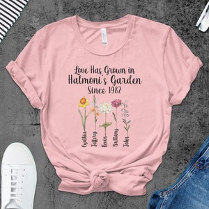 May include: Pink t-shirt with the text "Love Has Grown in Halmoni's Garden Since 1982" and a floral design. The names Cynthia, Jeffery, Kevin, Brittany, and John are listed below the flowers.