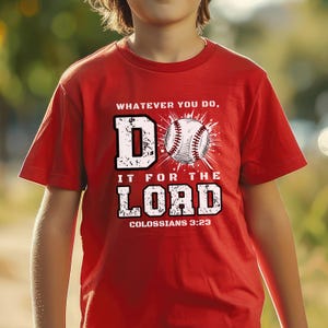 May include: A red short-sleeved t-shirt featuring a white graphic print that reads "WHATEVER YOU DO, DO IT FOR THE LORD" with a baseball replacing the letter "O" in "DO" and the text "COLOSSIANS 3:23" printed in white at the bottom of the design.