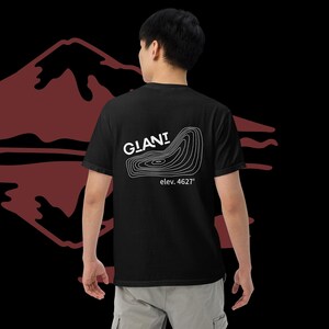 May include: Black t-shirt with a white graphic of a mountain contour and the word "GLANI" above the elevation "4627'". The shirt is made of a soft material and is a casual wear item.