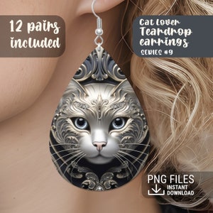 May include: A pair of silver teardrop earrings with a black and gold cat face design. The earrings are labeled "Cat Lover Teardrop Earrings Series #9".