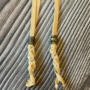A closeup view of the two different antique bronze charms attached to 2 tan notebook connectors.