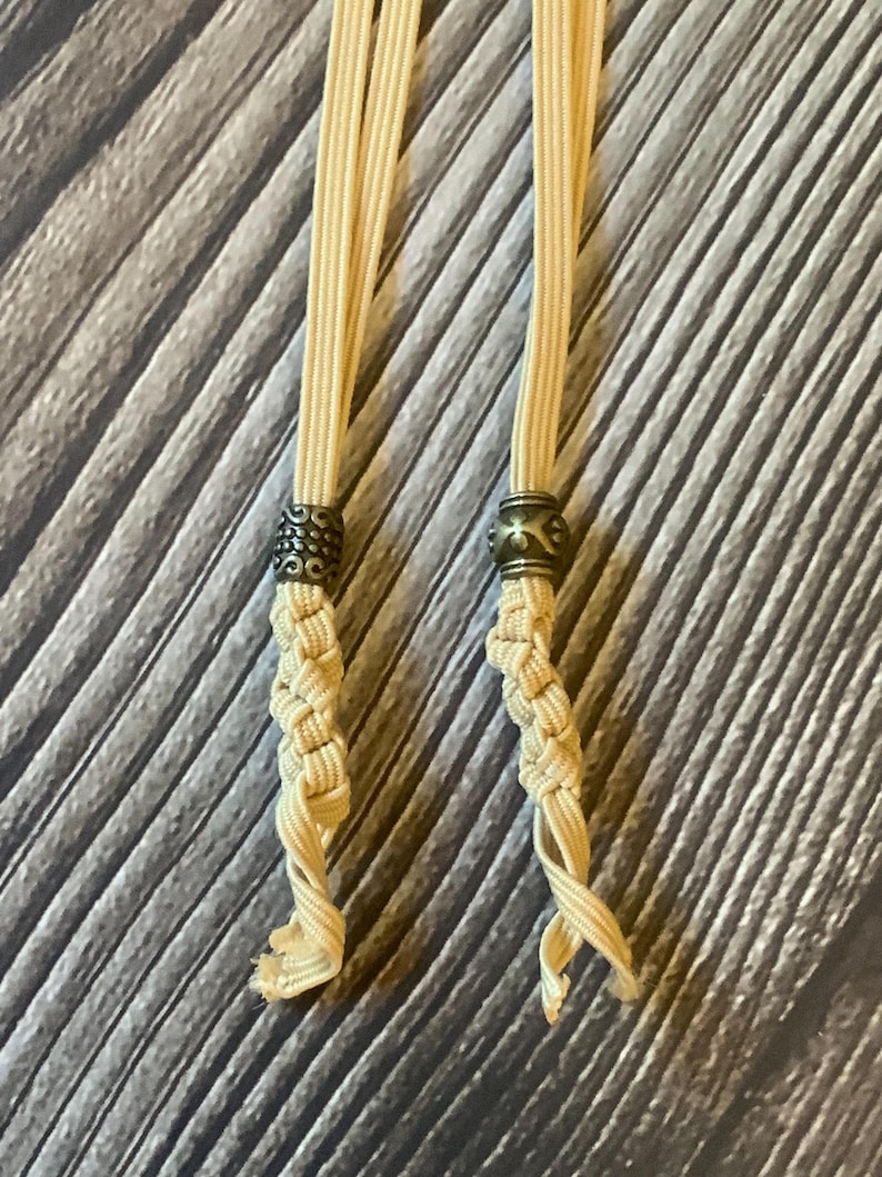 A closeup view of the two different antique bronze charms attached to 2 tan notebook connectors.