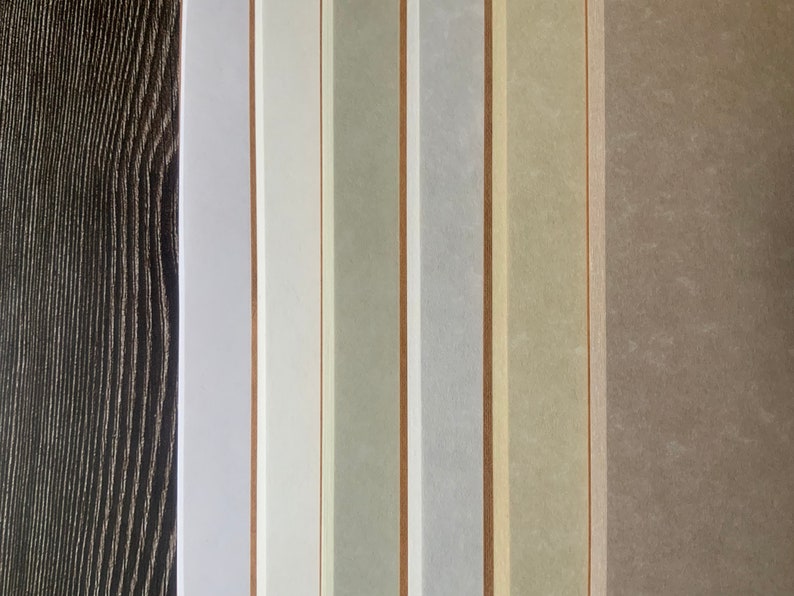 A close up of the 6 different colors of animal-free parchment paper available including white, fleece white, natural, storm, aged, and camel.  The speckled patterns of the animal-free parchment paper are shown in detail.
