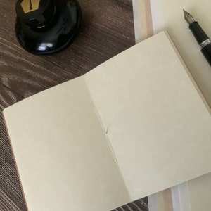 A single travelers notebook insert laying on a wooden surface.  The notebook insert is open, showcasing the speckled patterns of the animal-free parchment paper.