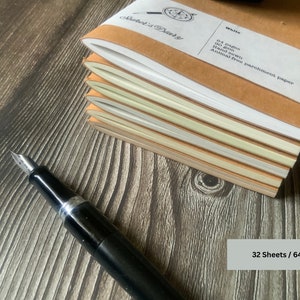 A stack of 6 travelers notebook inserts.  The picture is angled so that the edges of the papers are shown.  The differences in the 6 available page colors are apparent here, including white, fleece white, natural, storm, aged, and camel.