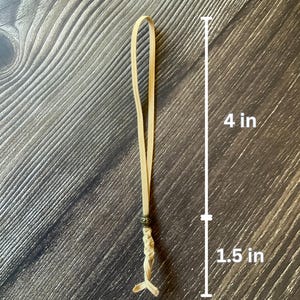 A tan notebook insert connector.  Measurements are shown.  The loop is 4 inches in length.  The decorative tail, including the antique bronze charm, adds an additional 1.5 inches in length.