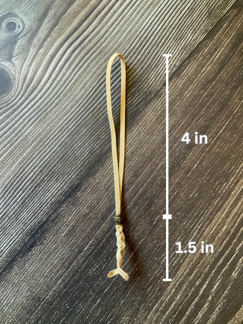 A tan notebook insert connector.  Measurements are shown.  The loop is 4 inches in length.  The decorative tail, including the antique bronze charm, adds an additional 1.5 inches in length.