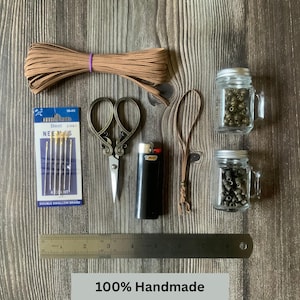 A handmade travelers notebook insert connector surrounded by the tools and materials used to create it.  Additional text at the bottom reads:  100% Handmade