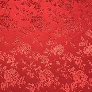 May include: Red fabric with a repeating pattern of roses and leaves. The roses are a slightly darker shade of red, creating a subtle contrast. The fabric has a textured appearance, with the floral design woven into the material.
