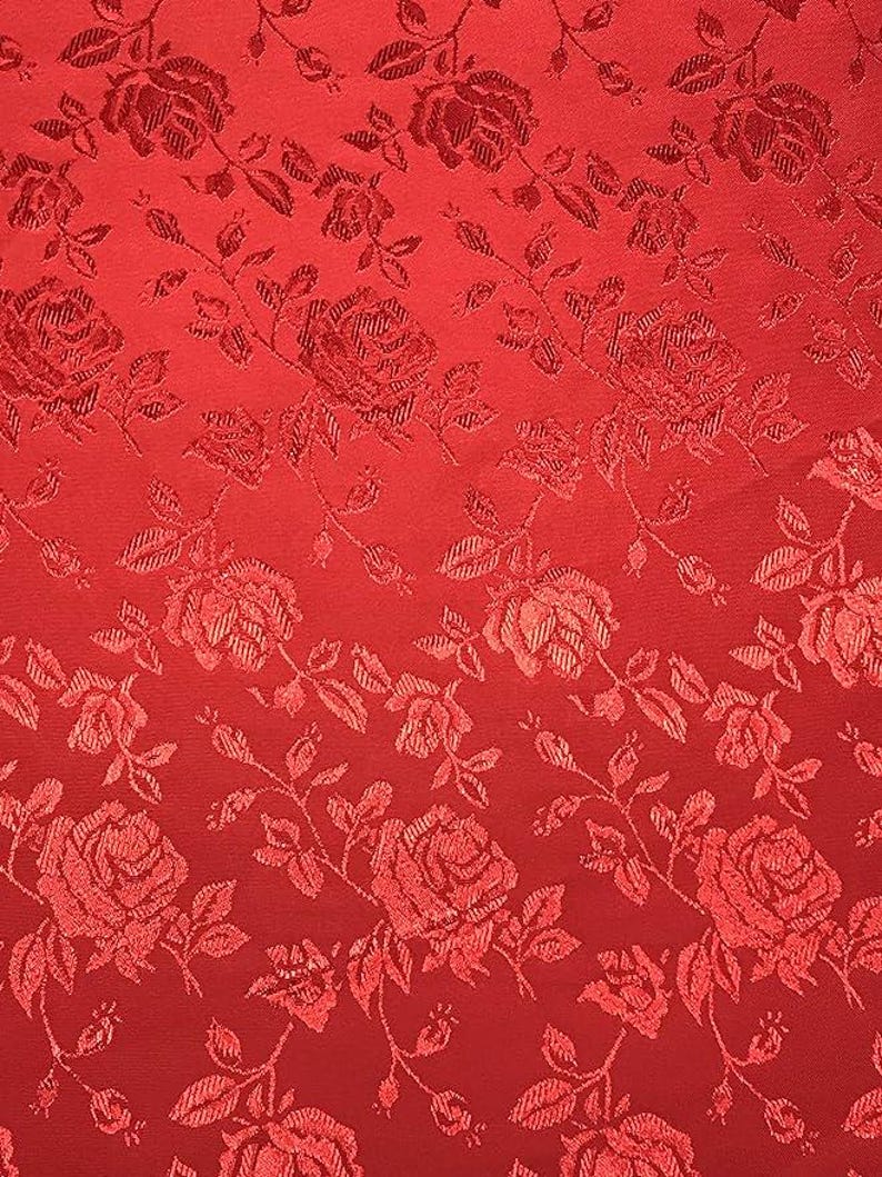 May include: Red fabric with a repeating pattern of roses and leaves. The roses are a slightly darker shade of red, creating a subtle contrast. The fabric has a textured appearance, with the floral design woven into the material.