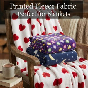 May include: Printed fleece blankets in a wooden chair. One blanket is white with red hearts, another is purple with colorful hearts, and the third is navy blue with moons and stars. The text "Printed Fleece Fabric Perfect for Blankets" is at the top.