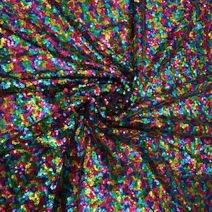 May include: A close-up of iridescent fabric with a rainbow of sequins. The sequins are arranged in a random pattern, creating a shimmering effect.