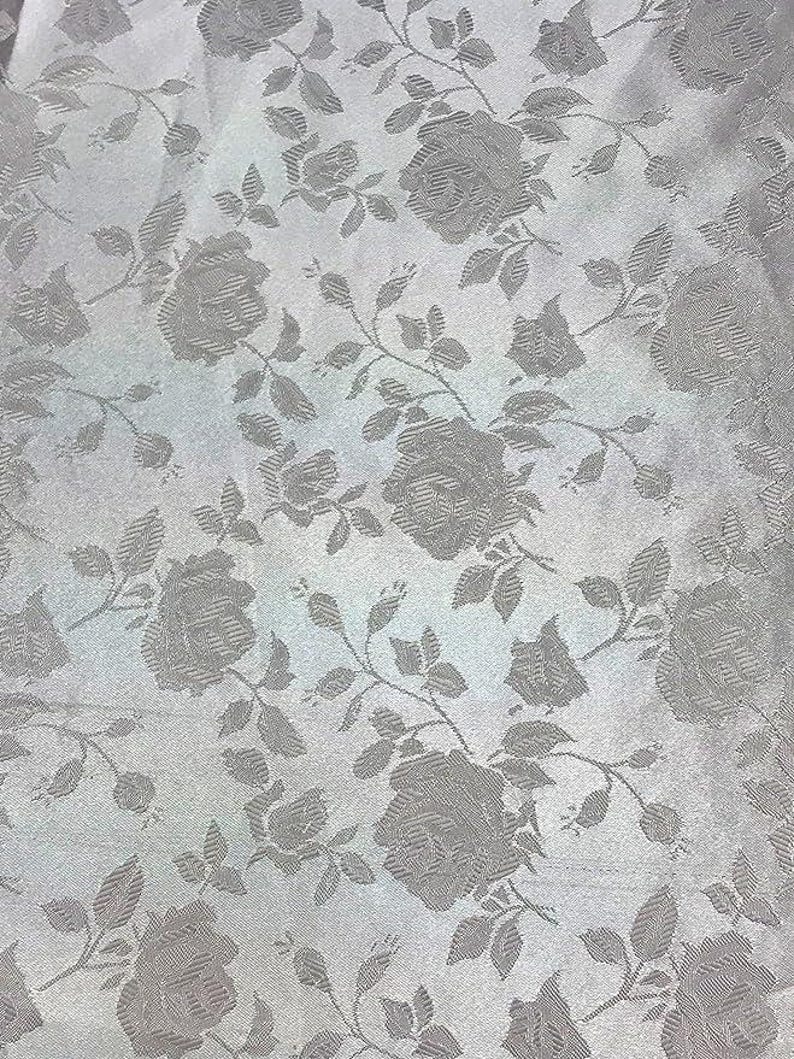 May include: A close-up of a fabric with a repeating pattern of roses and leaves in a light gray color. The roses are in full bloom and the leaves are detailed. The fabric has a subtle sheen.