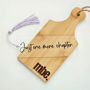 May include: A wooden bookmark with a clear acrylic insert that says "Just one more chapter..." and "mbe." The bookmark has a light purple tassel.
