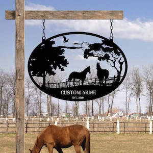 May include: Black metal oval sign with a silhouette of two horses in a field with trees and a fence. The sign has the text "CUSTOM NAME EST. 2024" at the bottom.