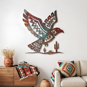 May include: Metal wall art of an eagle in flight, featuring a southwestern design. The eagle is in shades of red, brown, and turquoise, with geometric patterns on its wings. The artwork includes a desert scene with cacti.