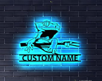 May include: A neon blue sign with a black silhouette of a gecko on a branch. The sign says "CUSTOM NAME" in a black font.