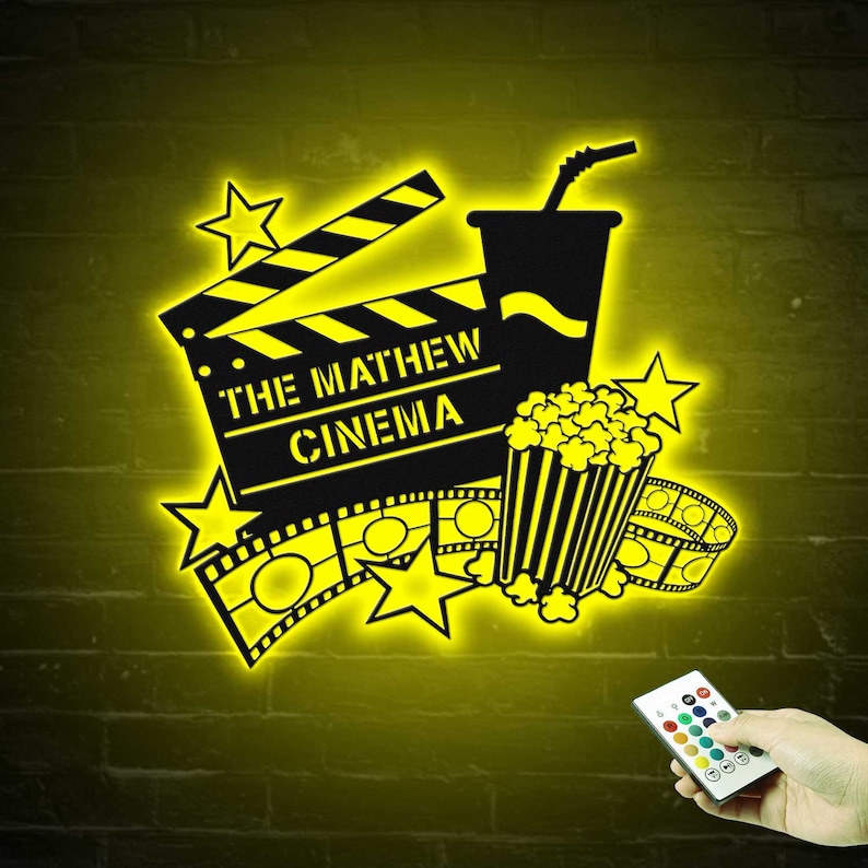 May include: A yellow neon sign with a movie clapperboard, popcorn bucket, and a drink. The clapperboard says "The Mathew Cinema".