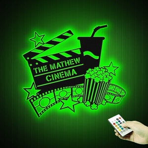 May include: Green glow-in-the-dark wall decal featuring a movie clapperboard, popcorn bucket, and film reel. The clapperboard reads "The Mathew Cinema".