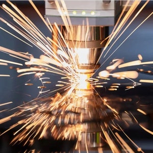 May include: A close-up of a laser cutting machine in operation, with sparks flying from the metal being cut.