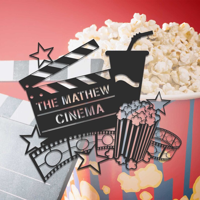 May include: A black and white illustration of a movie clapperboard with the text "The Mathew Cinema" on it. The image also includes a bucket of popcorn, a cup of soda, and a film reel.