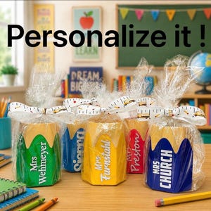 May include: A collection of pencil-shaped gifts, each wrapped in cellophane and tied with a bow. The pencils are in various colours, including green, blue, yellow, and red, and feature a teacher's name. The text "Personalize it!" is at the top.