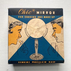 May include: Vintage "Chic Mirror" box with a blue and tan design. The box features illustrations of people shaving and applying makeup. Text on the box reads "For Shaving and Make Up" and "Genuine Porcelain Base".