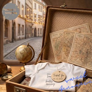 Puede incluir: Un body blanco para bebé con el texto "new tray buddy arriving" y una etiqueta de madera que dice "Ticket for 05.12.2024". El body está dentro de una maleta vintage abierta con mapas de París, Roma y Tokio.