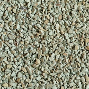 Op de afbeelding: Close-up van een hoop kleine, groene en bruine grind. De grind is onregelmatig gevormd en heeft een ruwe textuur.