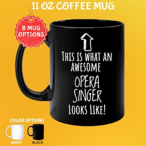 Könnte beinhalten: Schwarze 325 ml Kaffeetasse mit dem weißen Text "THIS IS WHAT AN AWESOME OPERA SINGER LOOKS LIKE!". Die Tasse hat einen schwarzen Henkel und eine weiße Pfeilgrafik. Farboptionen sind Weiß und Schwarz.