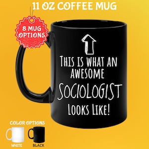 Peut inclure: Mug à café noir de 325 ml avec le texte "THIS IS WHAT AN AWESOME SOCIOLOGIST LOOKS LIKE!" en blanc. La tasse a une anse noire et un graphique de flèche. Options de couleur : tasses blanches et noires.
