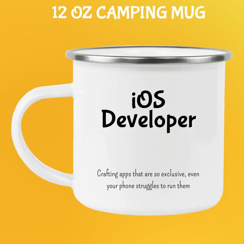 May include: White 355 ml camping mug with a silver rim and handle. The mug features the text "iOS Developer" in black, along with a humorous quote about app development. The mug is designed for outdoor use.