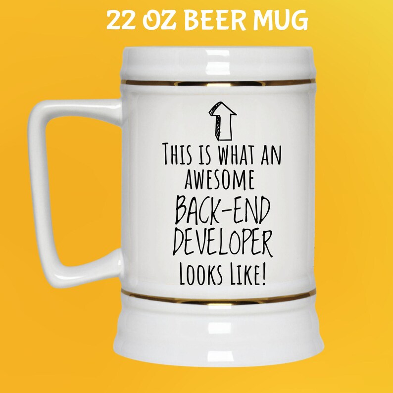 Op de afbeelding: Witte 650 ml bierpul met gouden rand en een handvat. De pul heeft de zwarte tekst "THIS IS WHAT AN AWESOME BACK-END DEVELOPER LOOKS LIKE!". De tekst "22 OZ BEER MUG" staat bovenaan.