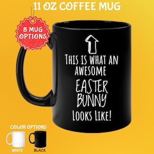 May include: Black 11 oz coffee mug with the text "THIS IS WHAT AN AWESOME EASTER BUNNY LOOKS LIKE!" in white. The mug has a black handle and a white arrow graphic. Color options include white and black mugs.