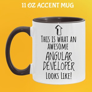 May include: White 11 oz accent mug with a black handle and rim. The mug features the text "THIS IS WHAT AN AWESOME ANGULAR DEVELOPER LOOKS LIKE!" in black, with an arrow graphic.